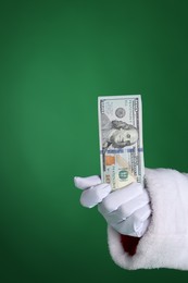 Photo of Santa Claus holding dollar banknotes on green background, closeup. Space for text