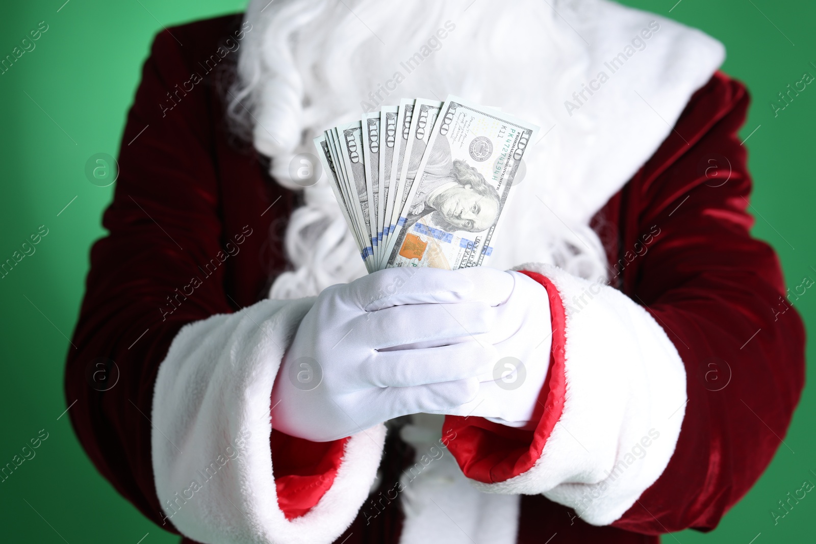 Photo of Santa Claus holding dollar banknotes on green background, closeup