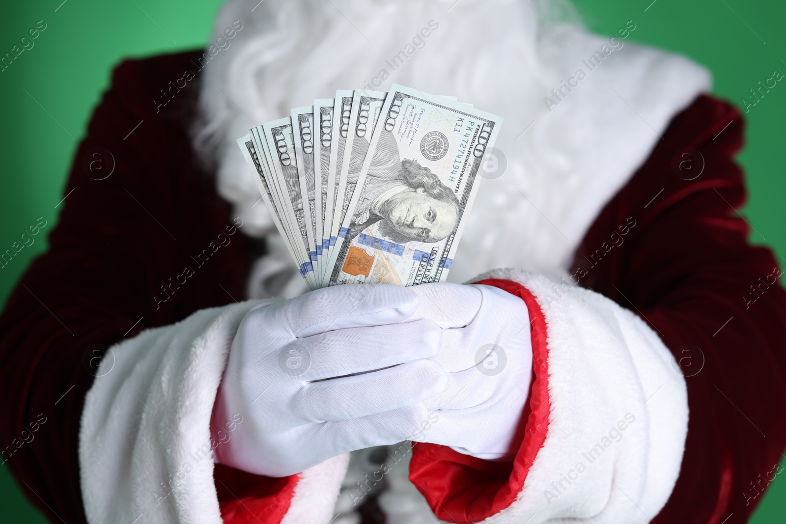 Photo of Santa Claus holding dollar banknotes on green background, closeup