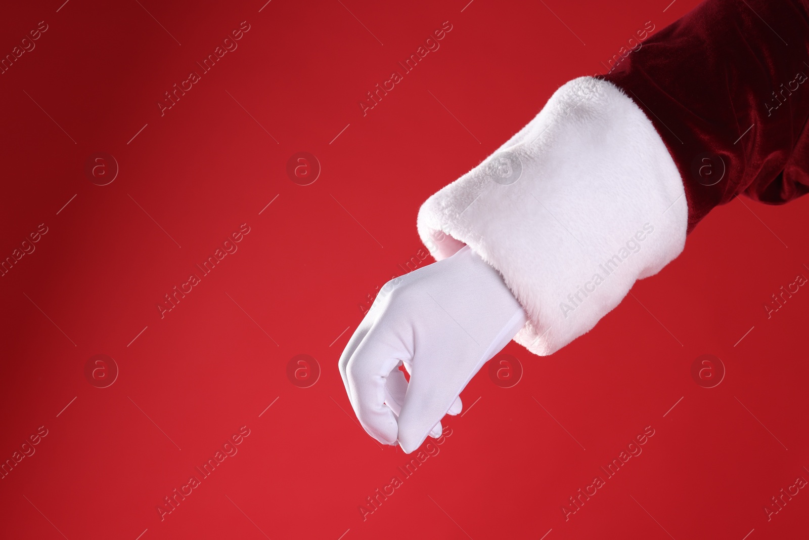 Photo of Santa Claus holding something on red background, closeup. Space for text