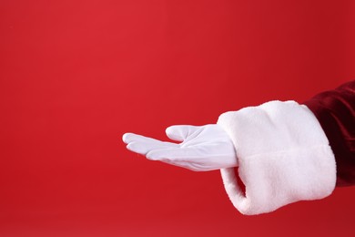 Photo of Santa Claus holding something on red background, closeup. Space for text