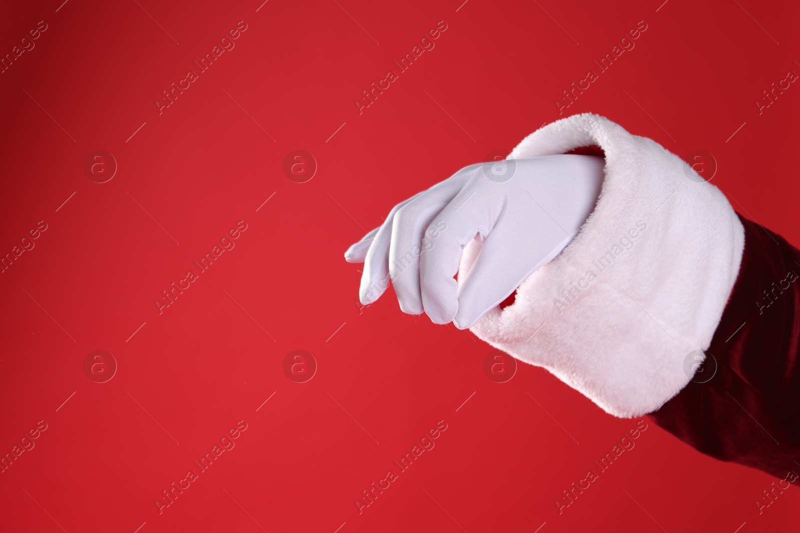 Photo of Santa Claus holding something on red background, closeup. Space for text