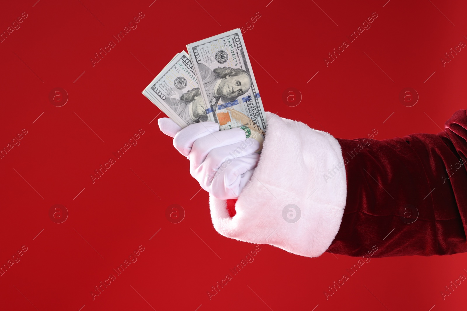 Photo of Santa Claus holding dollar banknotes on red background, closeup. Space for text