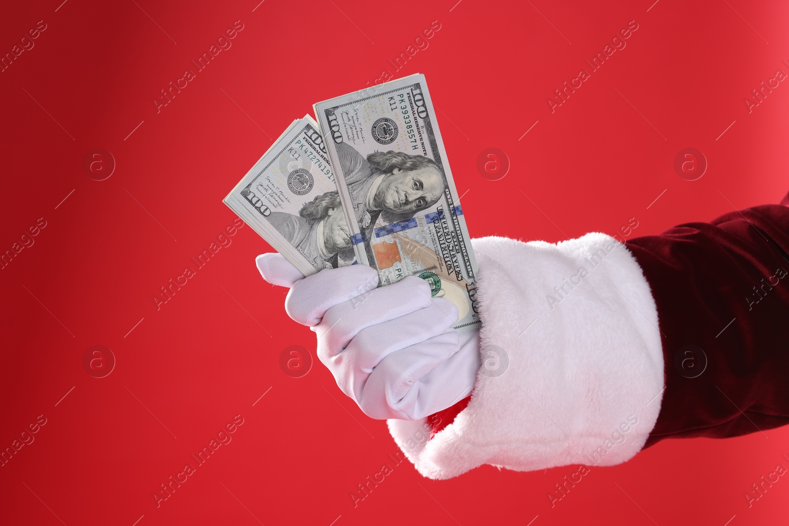 Photo of Santa Claus holding dollar banknotes on red background, closeup. Space for text