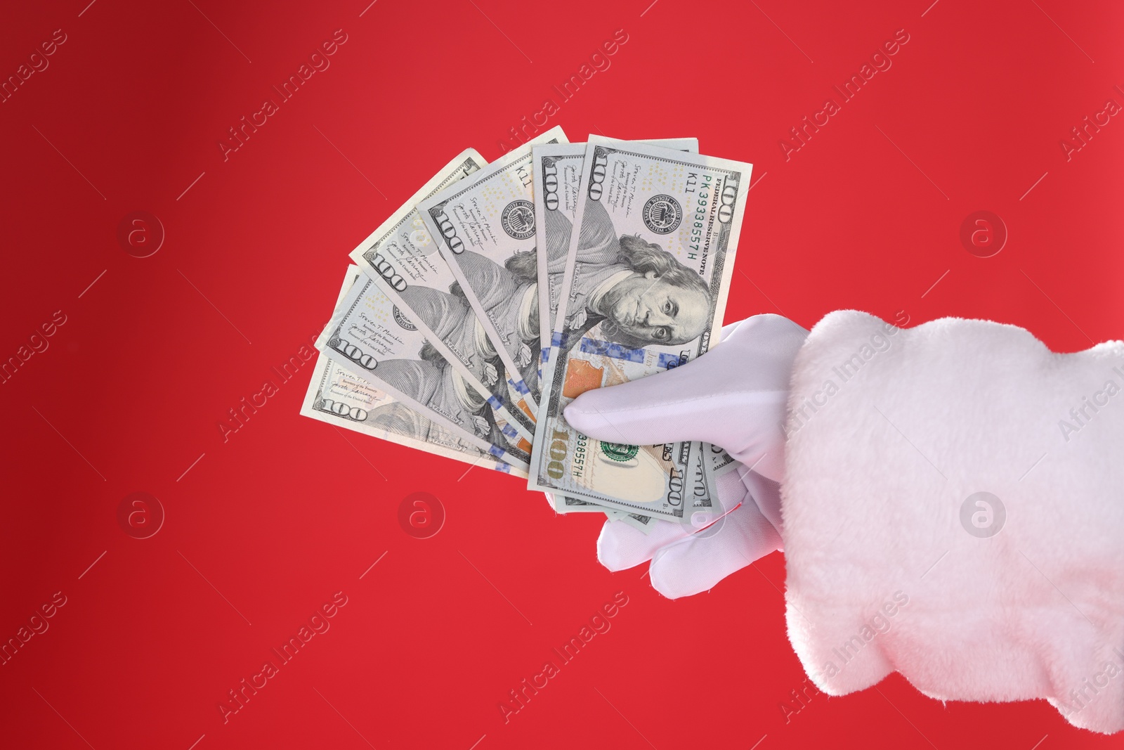 Photo of Santa Claus holding dollar banknotes on red background, closeup