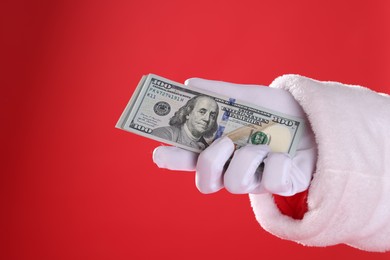 Photo of Santa Claus holding dollar banknotes on red background, closeup. Space for text