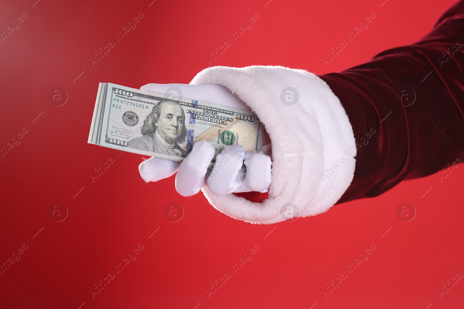 Photo of Santa Claus holding dollar banknotes on red background, closeup