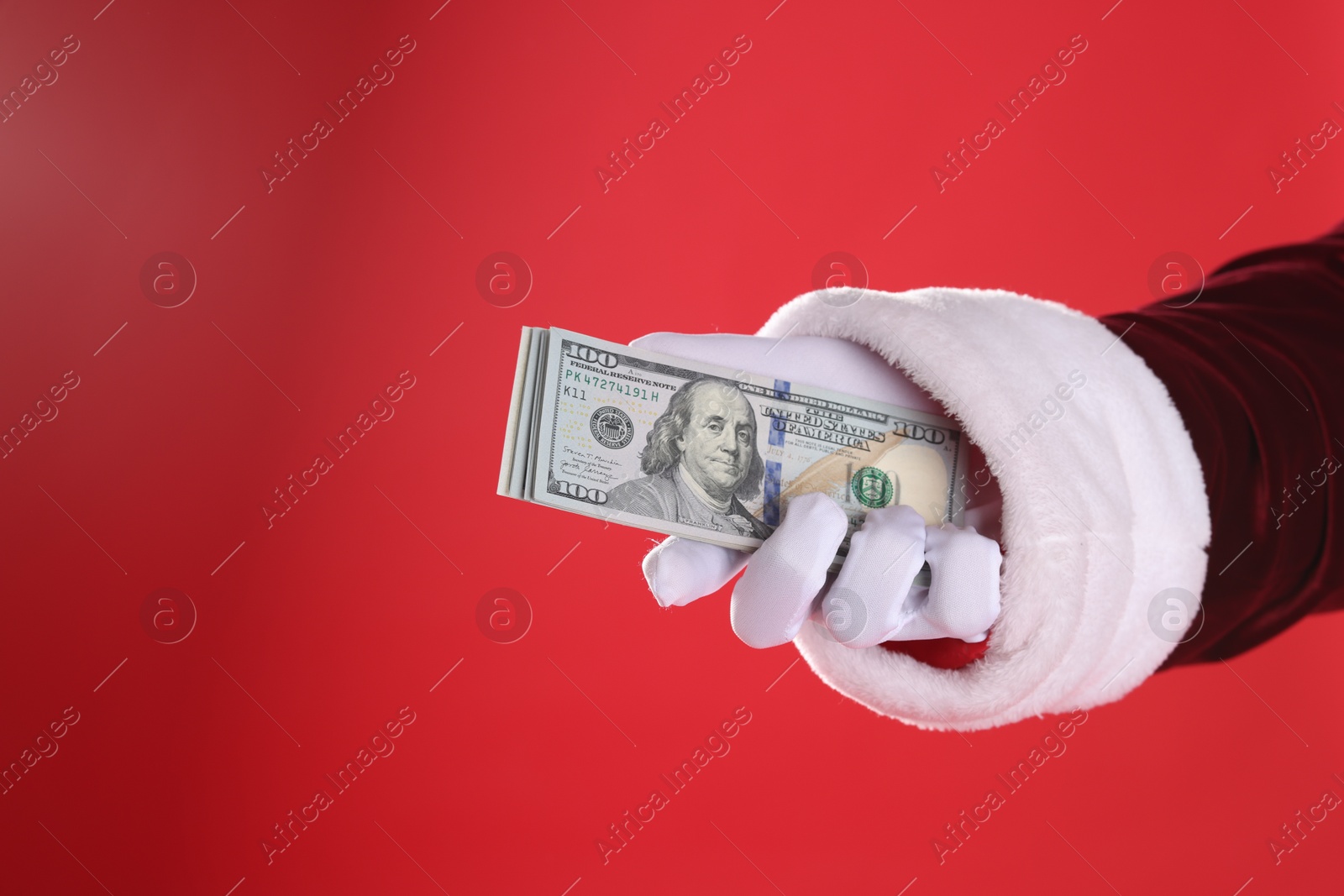 Photo of Santa Claus holding dollar banknotes on red background, closeup. Space for text