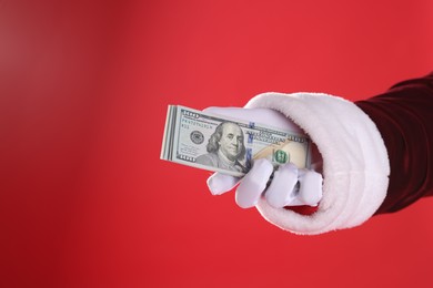 Santa Claus holding dollar banknotes on red background, closeup. Space for text