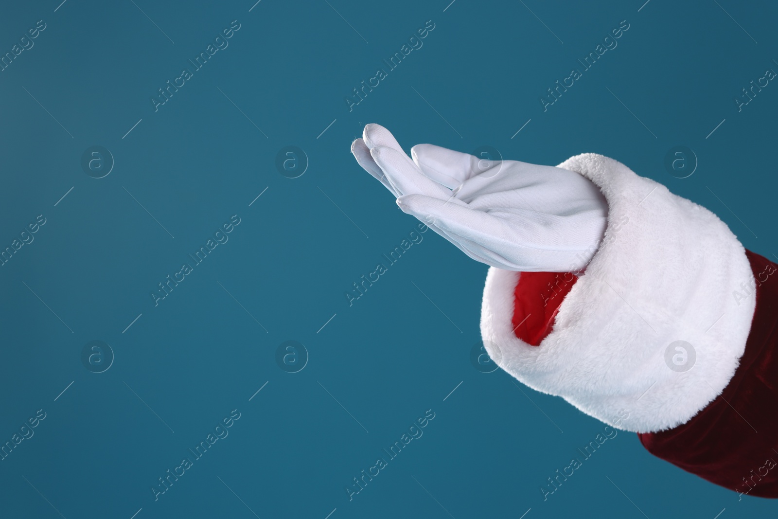 Photo of Santa Claus holding something on blue background, closeup. Space for text