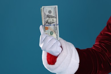 Santa Claus holding dollar banknotes on blue background, closeup