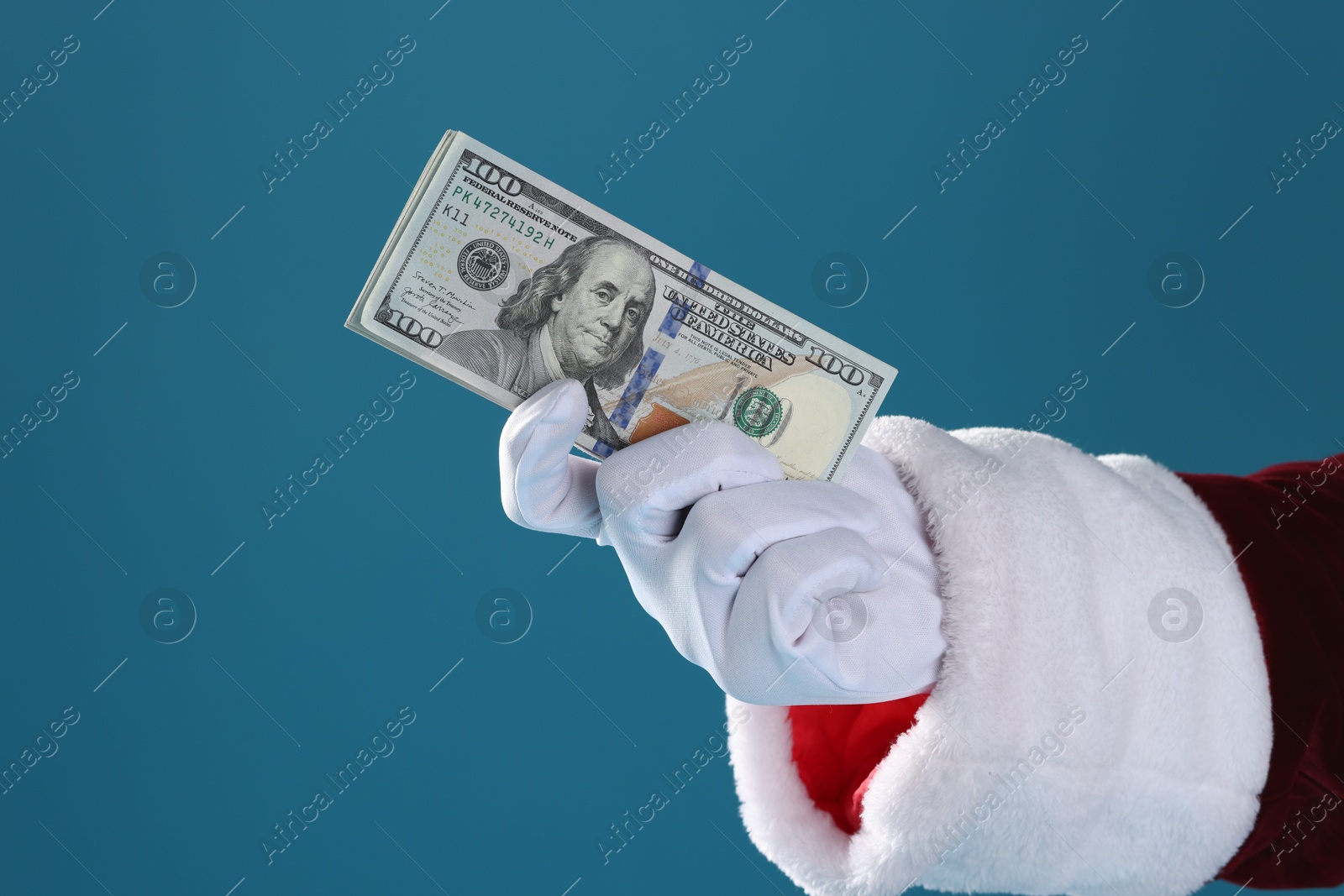 Photo of Santa Claus holding dollar banknotes on blue background, closeup