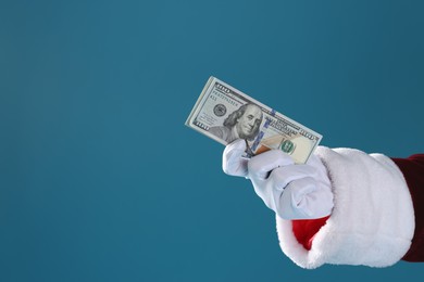 Photo of Santa Claus holding dollar banknotes on blue background, closeup. Space for text