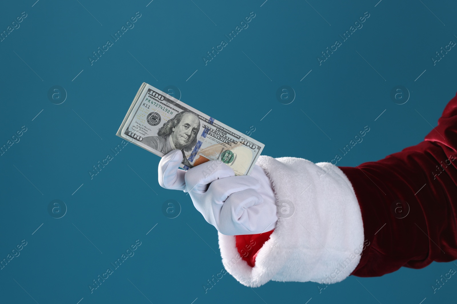 Photo of Santa Claus holding dollar banknotes on blue background, closeup