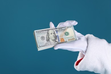 Photo of Santa Claus holding dollar banknotes on blue background, closeup. Space for text