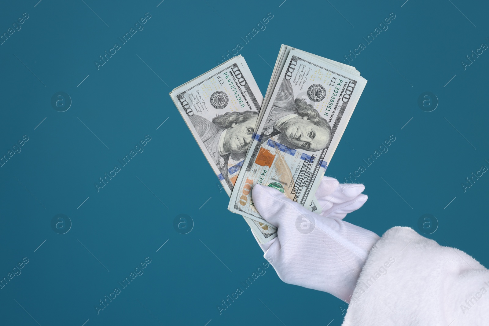 Photo of Santa Claus holding dollar banknotes on blue background, closeup. Space for text