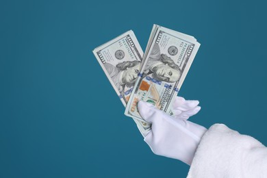 Photo of Santa Claus holding dollar banknotes on blue background, closeup. Space for text