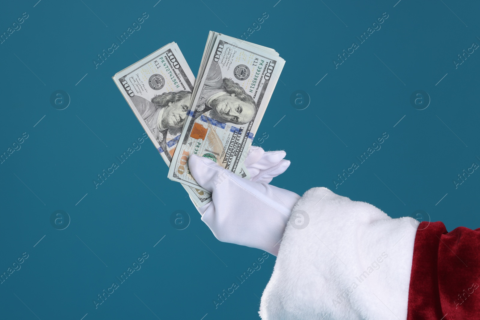 Photo of Santa Claus holding dollar banknotes on blue background, closeup