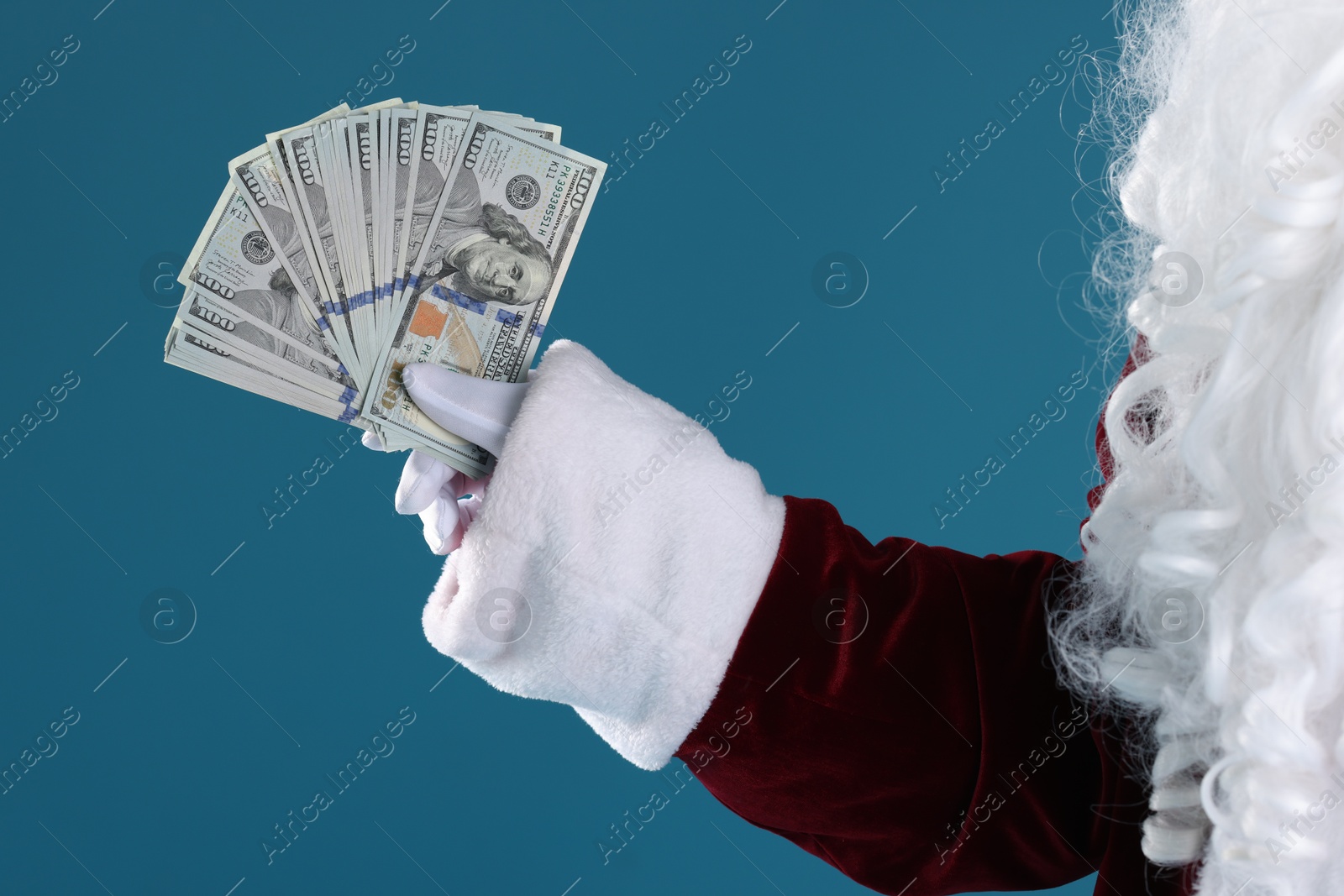 Photo of Santa Claus holding dollar banknotes on blue background, closeup