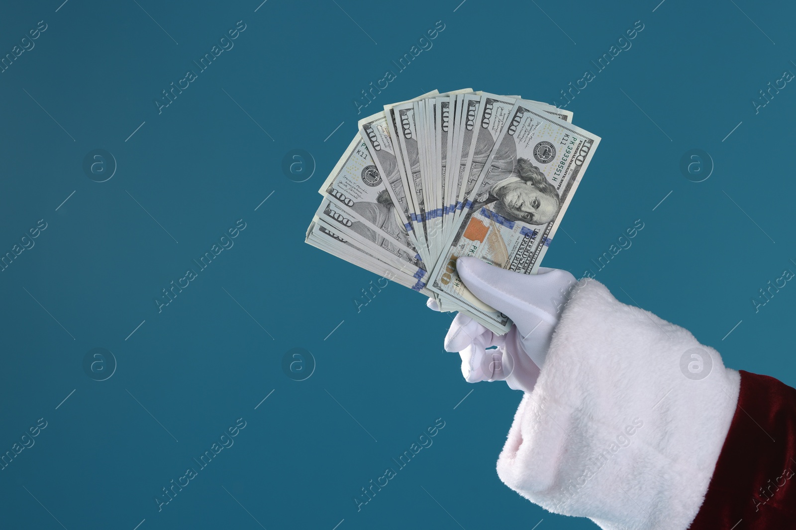 Photo of Santa Claus holding dollar banknotes on blue background, closeup. Space for text