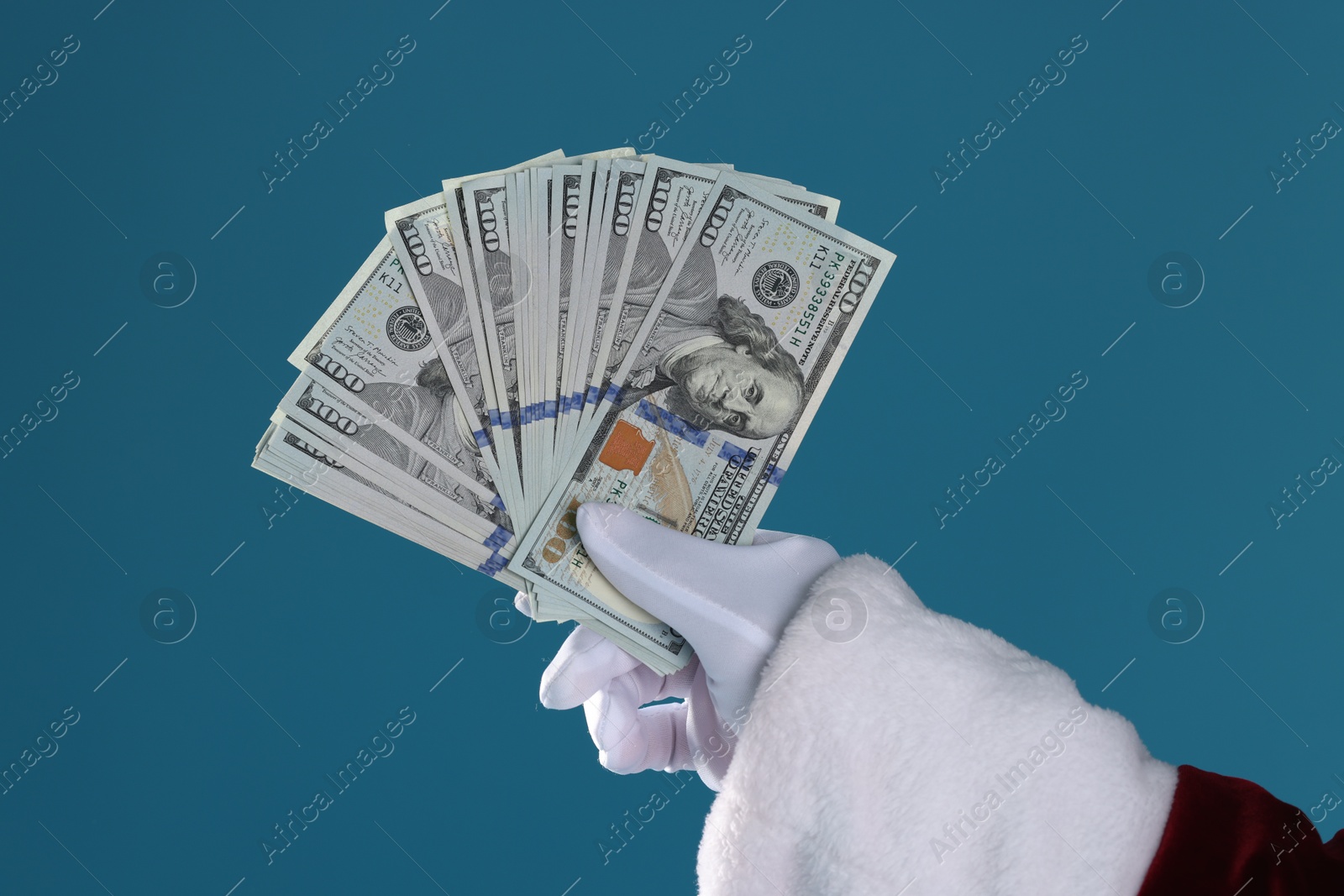 Photo of Santa Claus holding dollar banknotes on blue background, closeup