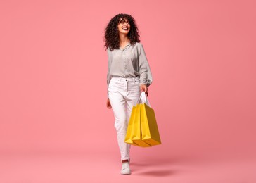 Smiling woman with shopping bags on pink background