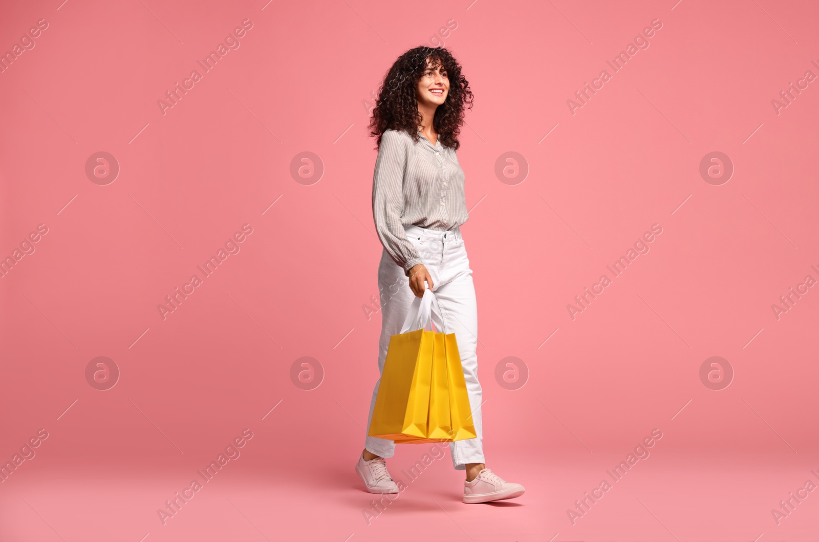 Photo of Smiling woman with shopping bags on pink background