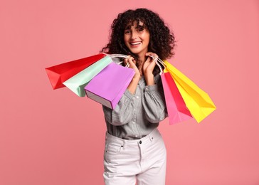 Photo of Smiling woman with colorful shopping bags on pink background