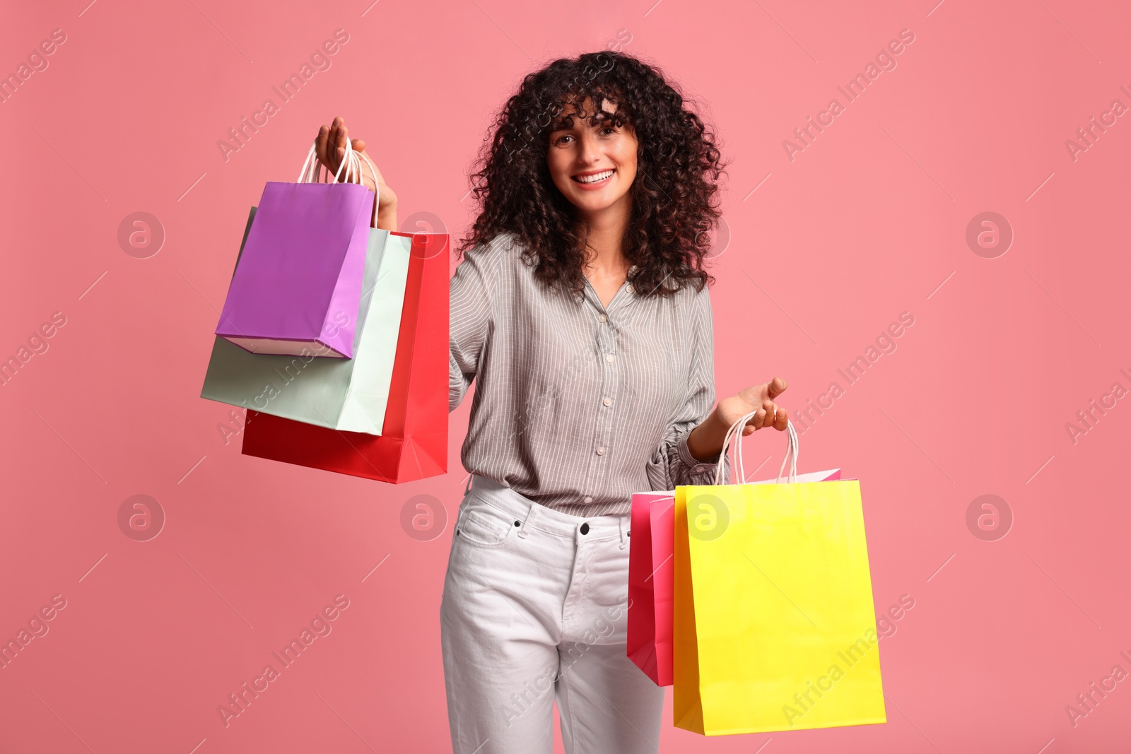 Photo of Smiling woman with colorful shopping bags on pink background