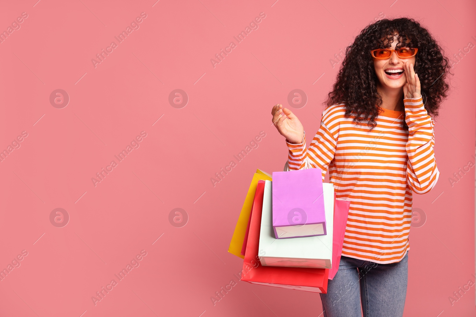 Photo of Happy woman with colorful shopping bags on pink background. Space for text