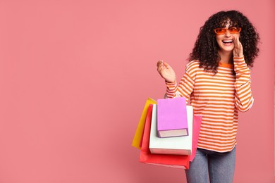 Happy woman with colorful shopping bags on pink background. Space for text