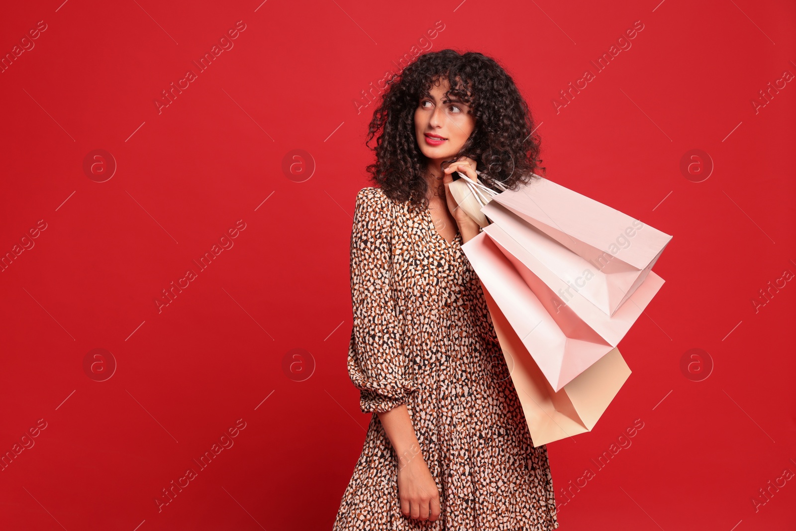 Photo of Beautiful woman with shopping bags on red background. Space for text