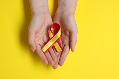 Photo of Woman with colorful ribbon on yellow background, top view. Hepatitis C awareness