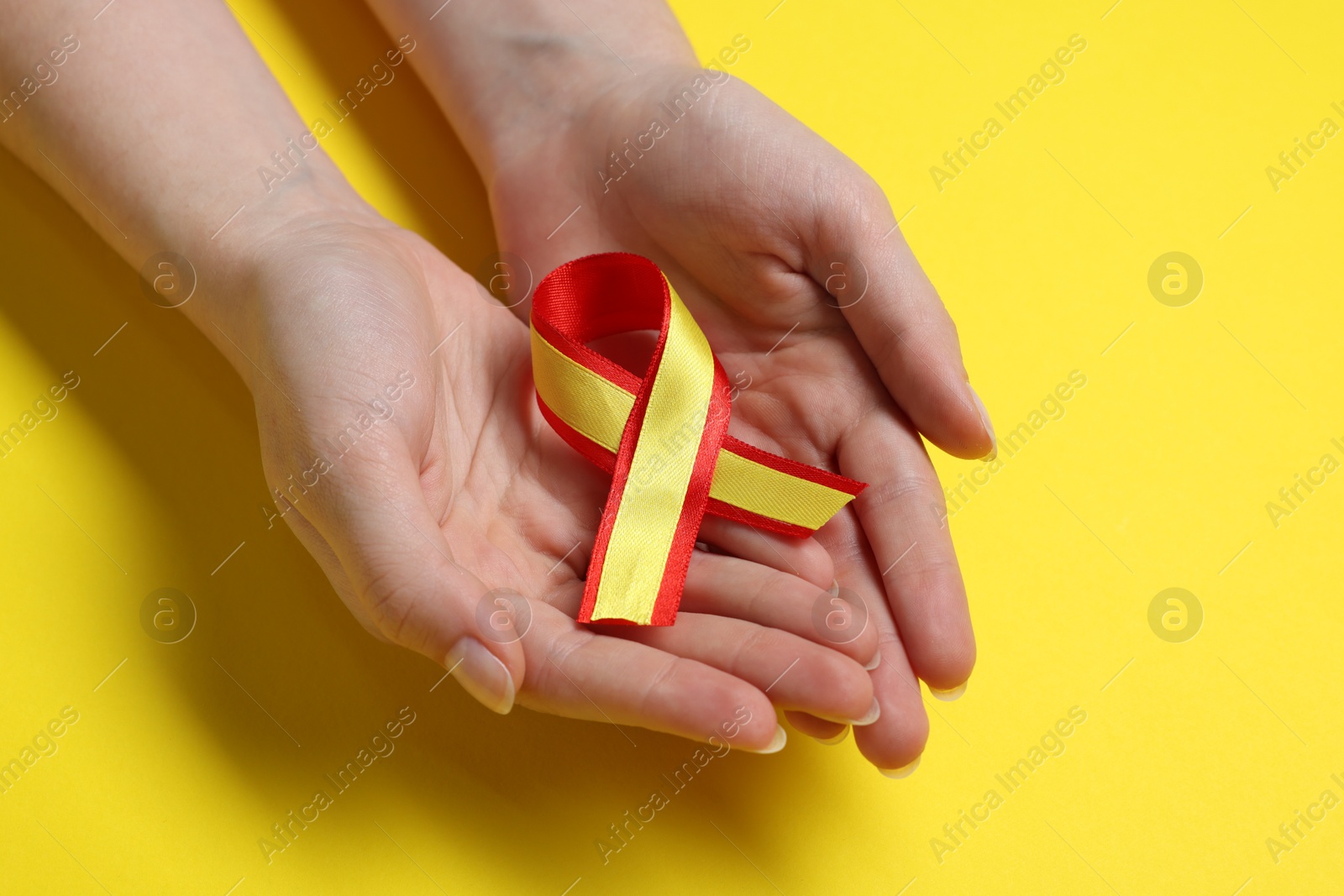 Photo of Woman with colorful ribbon on yellow background, closeup. Hepatitis C awareness