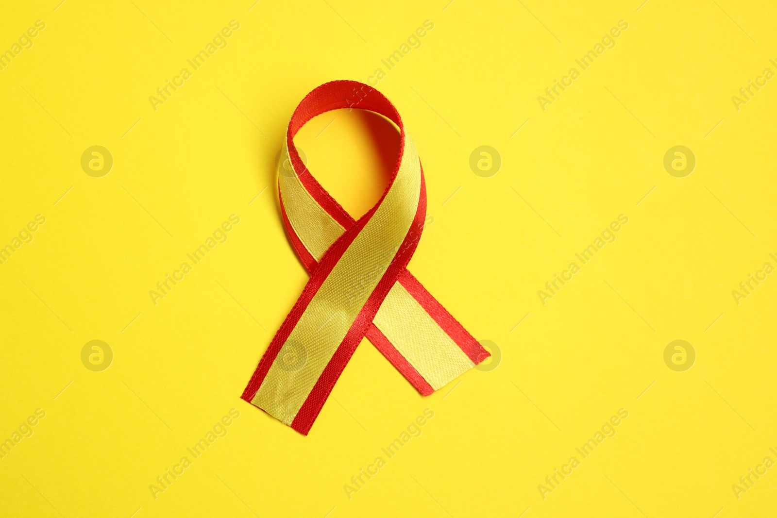 Photo of One colorful ribbon on yellow background, top view. Hepatitis C awareness