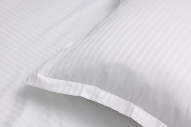 Bed with white clean linens and pillow, closeup