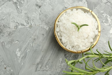 Photo of Sea salt and rosemary in bowl on gray textured table, flat lay. Space for text