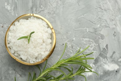 Photo of Sea salt and rosemary in bowl on gray textured table, flat lay. Space for text