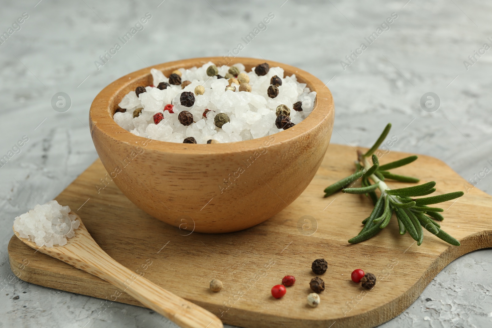 Photo of Sea salt and spices in bowl on gray textured table, closeup