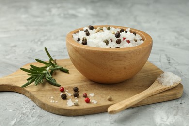 Photo of Sea salt and spices in bowl on gray textured table, closeup