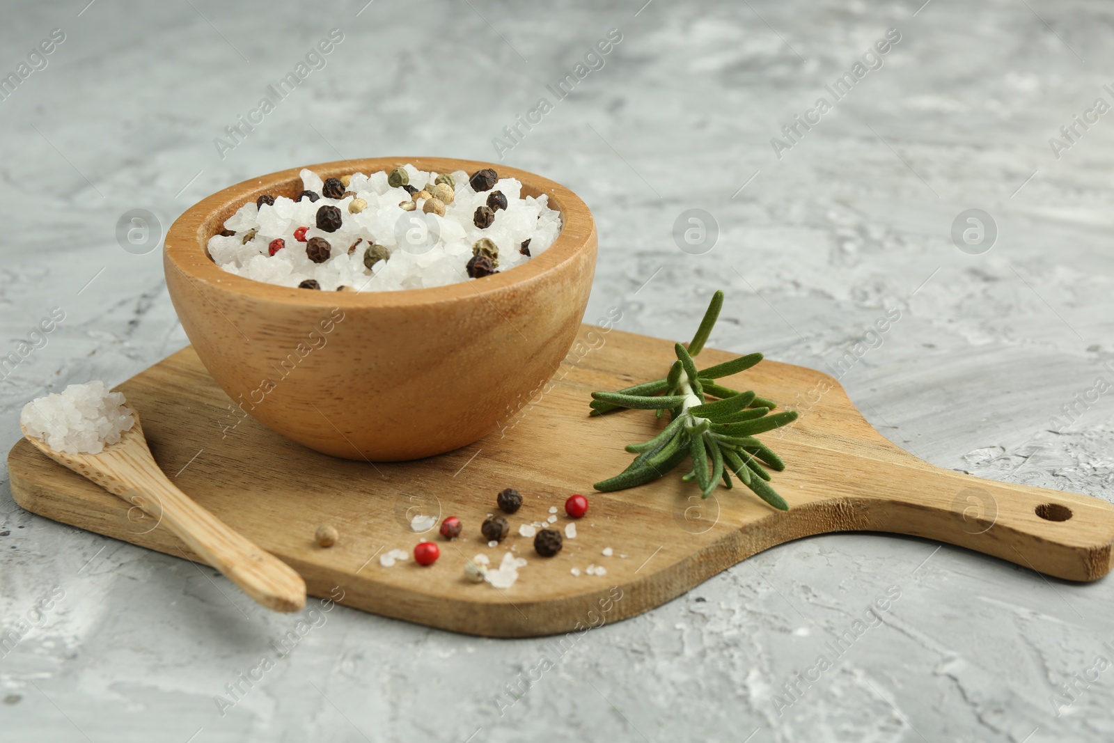 Photo of Sea salt and spices in bowl on gray textured table