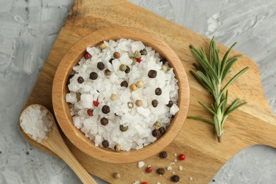 Sea salt and spices in bowl on gray textured table, top view