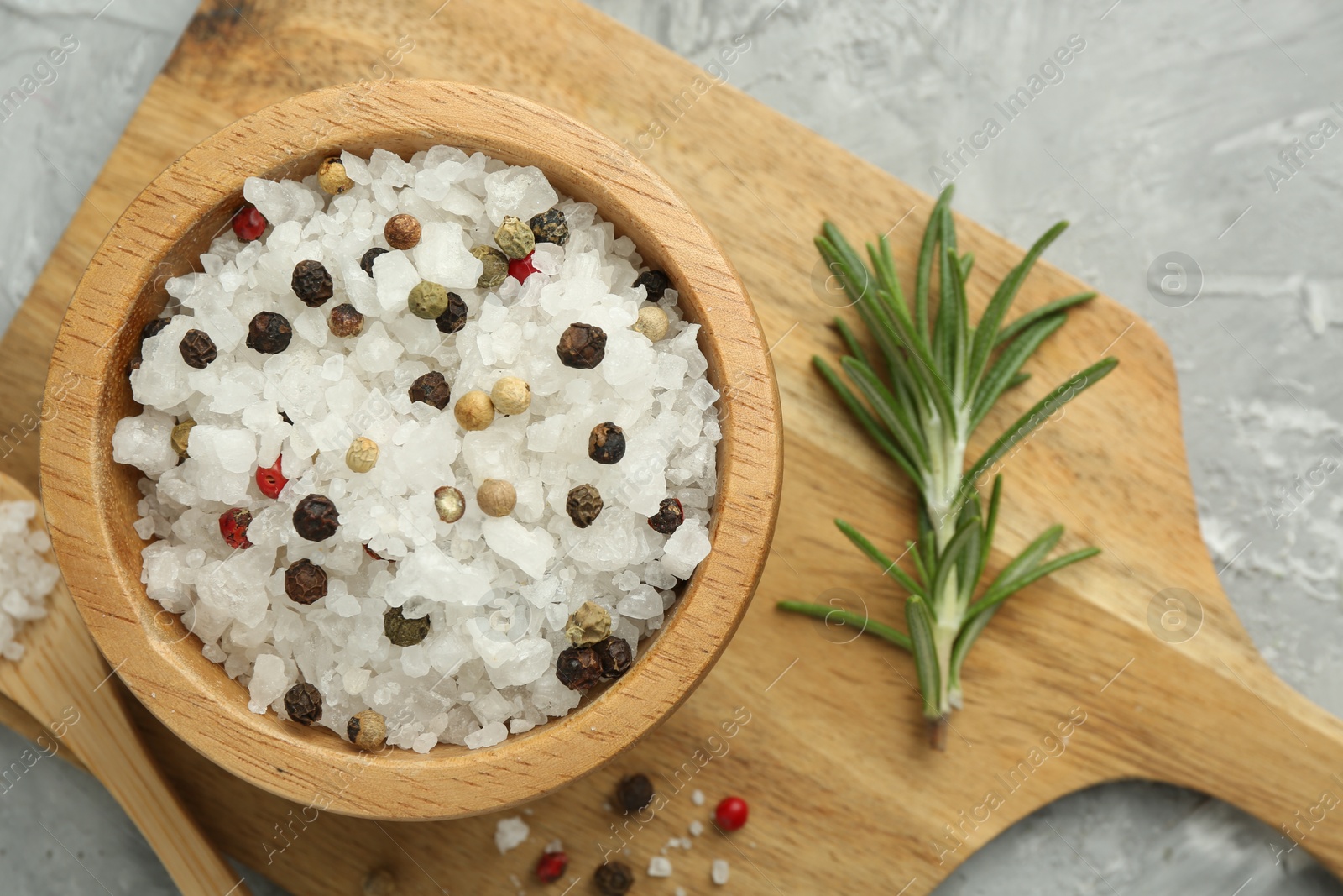 Photo of Sea salt and spices in bowl on gray textured table, top view