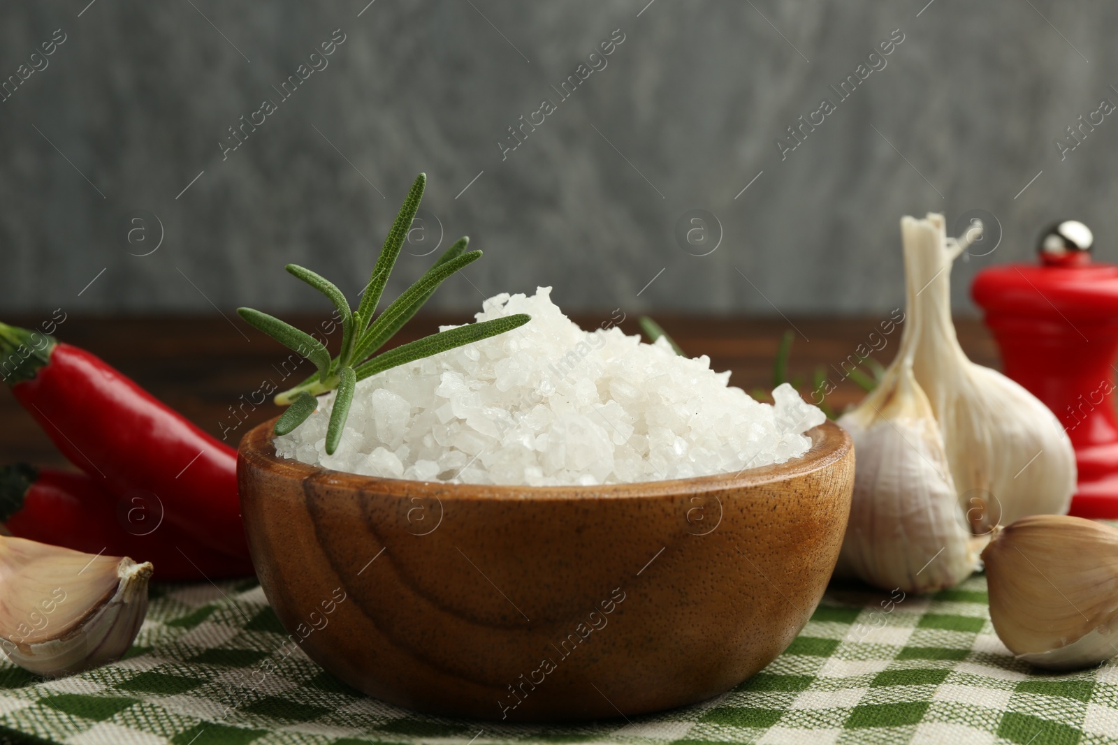 Photo of Sea salt in bowl and spices on table, closeup