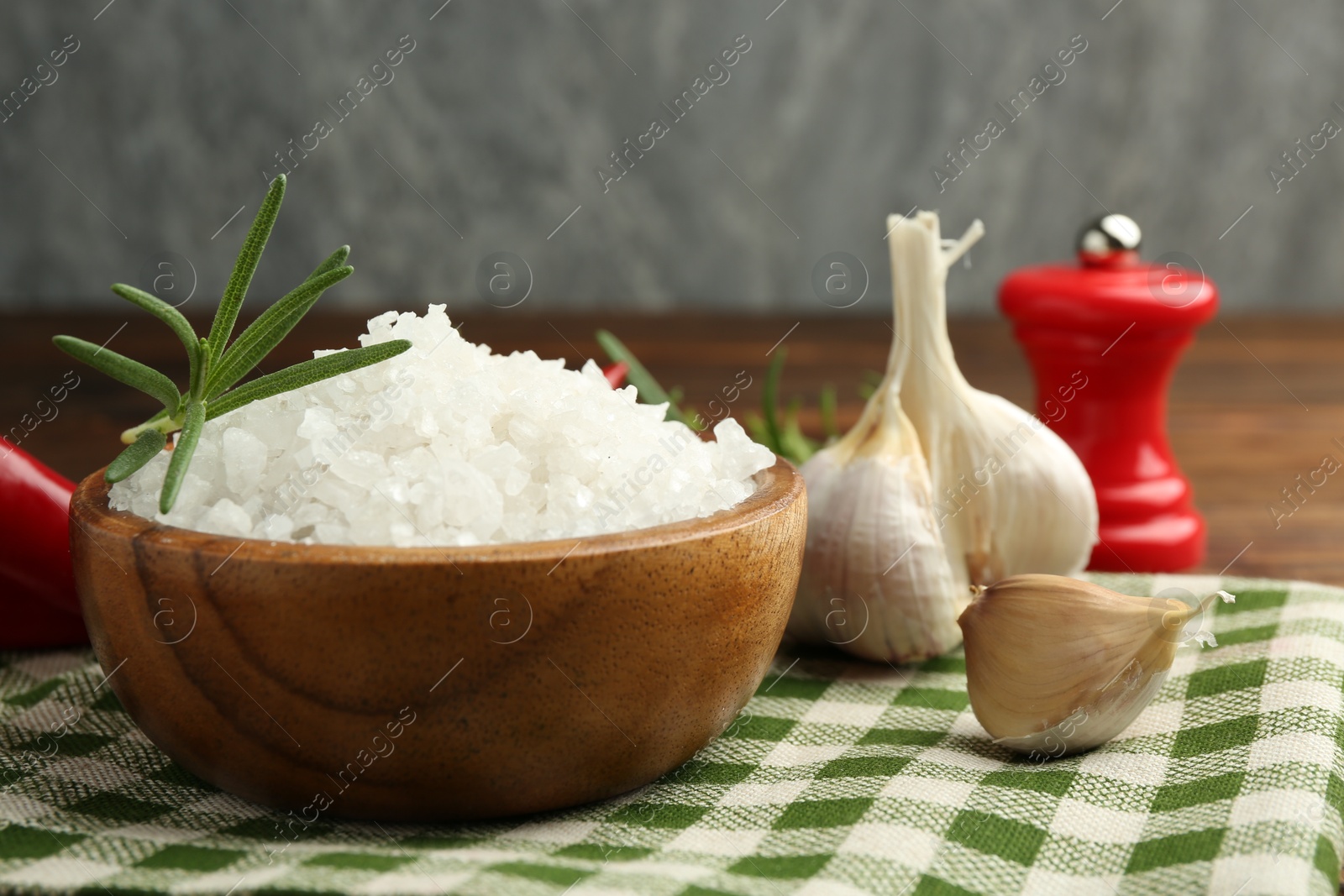 Photo of Sea salt in bowl and spices on table, closeup