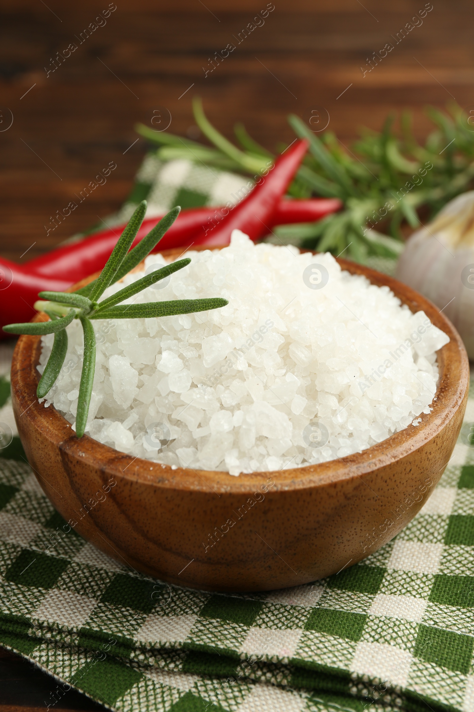 Photo of Sea salt in bowl and spices on table, closeup