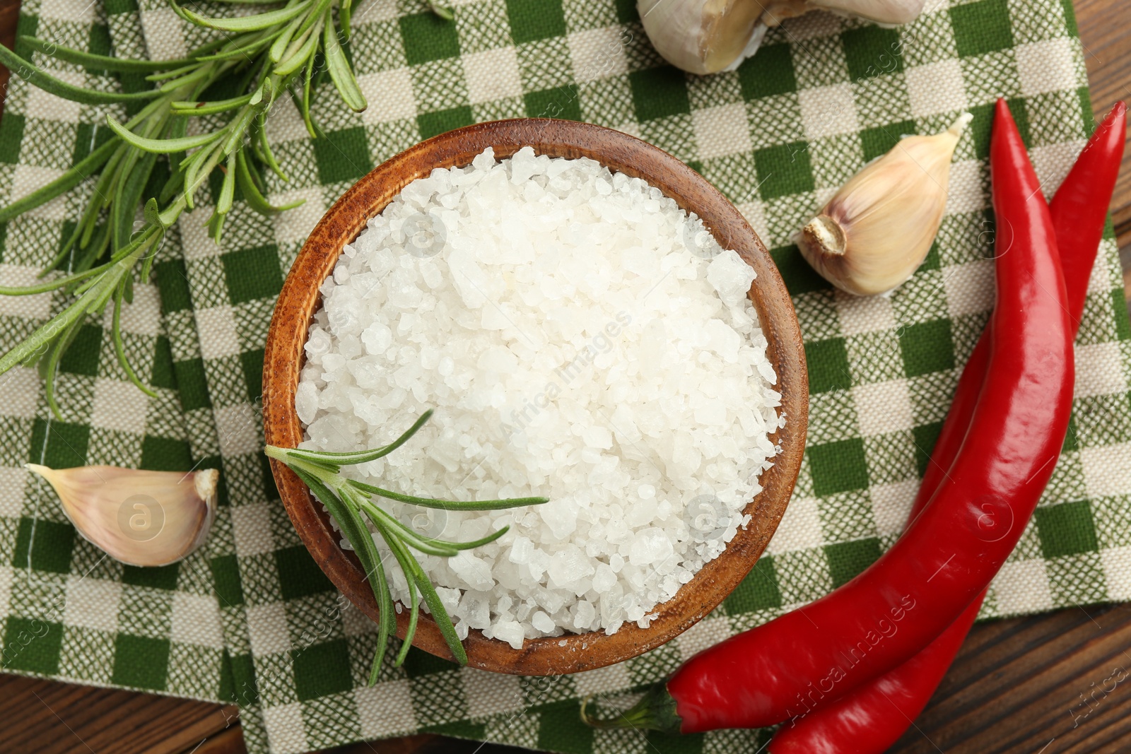 Photo of Sea salt in bowl and spices on table, flat lay