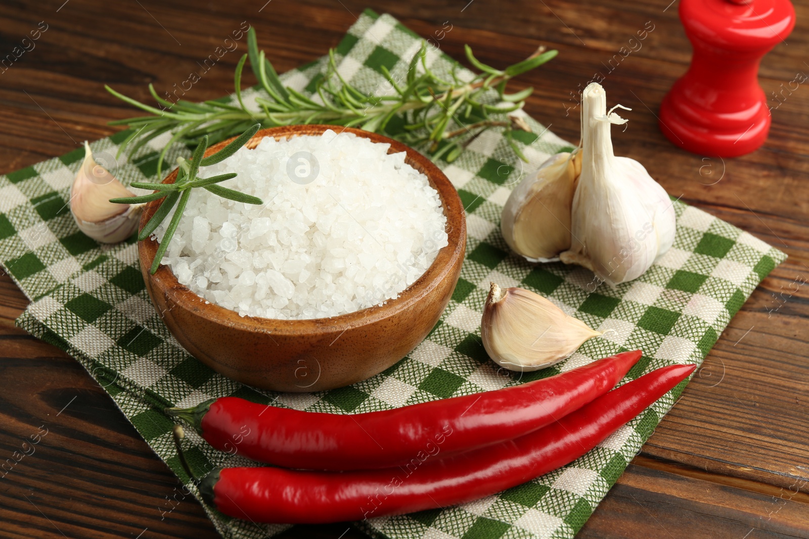 Photo of Sea salt in bowl and spices on wooden table, closeup