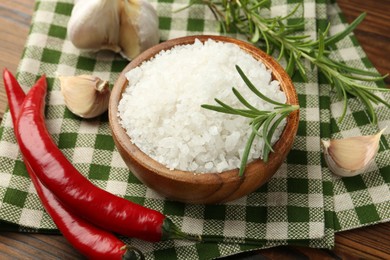 Photo of Sea salt in bowl and spices on table, closeup