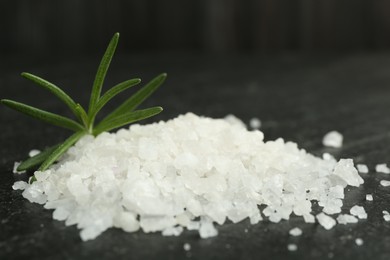 Sea salt and rosemary on dark gray textured table, closeup